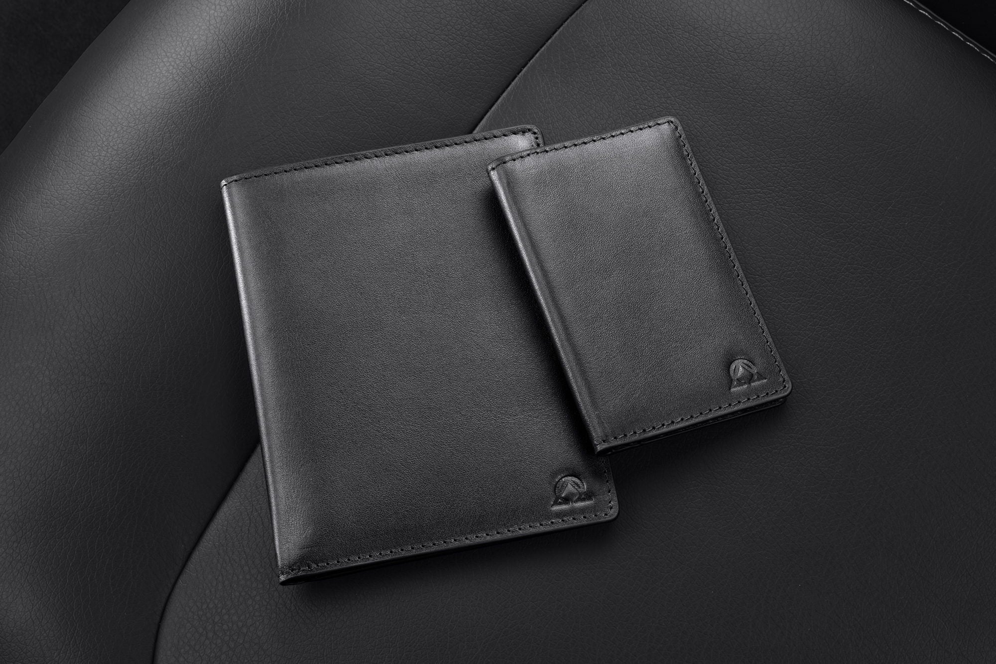 Two black leather wallets on a leather seat — DARMA