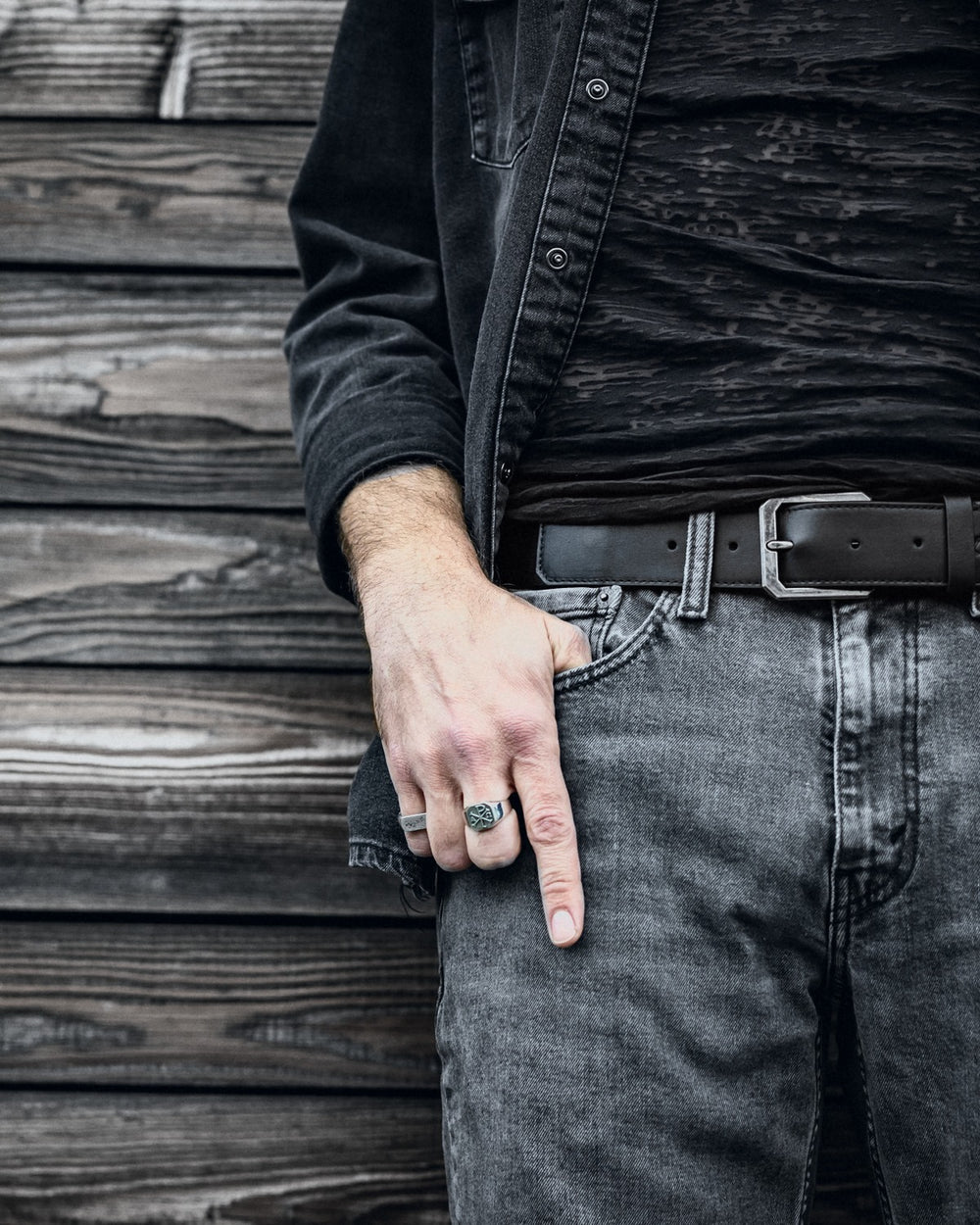 Praxis Belt in Onyx full-grain leather buckled at the waist with grey denim and a silver ring.