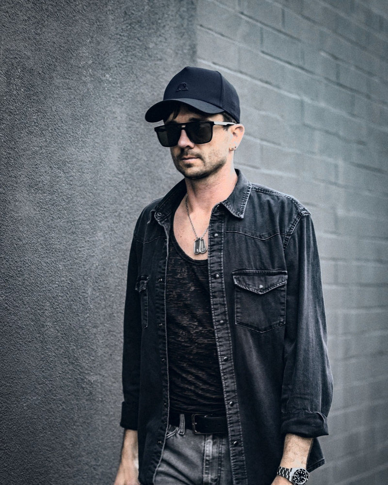 Lux Trucker hat in Onyx worn with a black denim shirt.