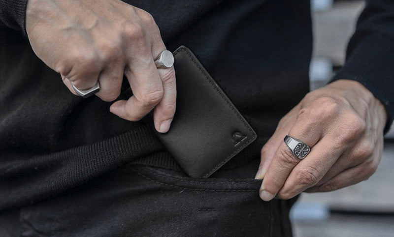 Nexus Wallet in Onyx slipped into a pocket, silver signet rings on both hands.