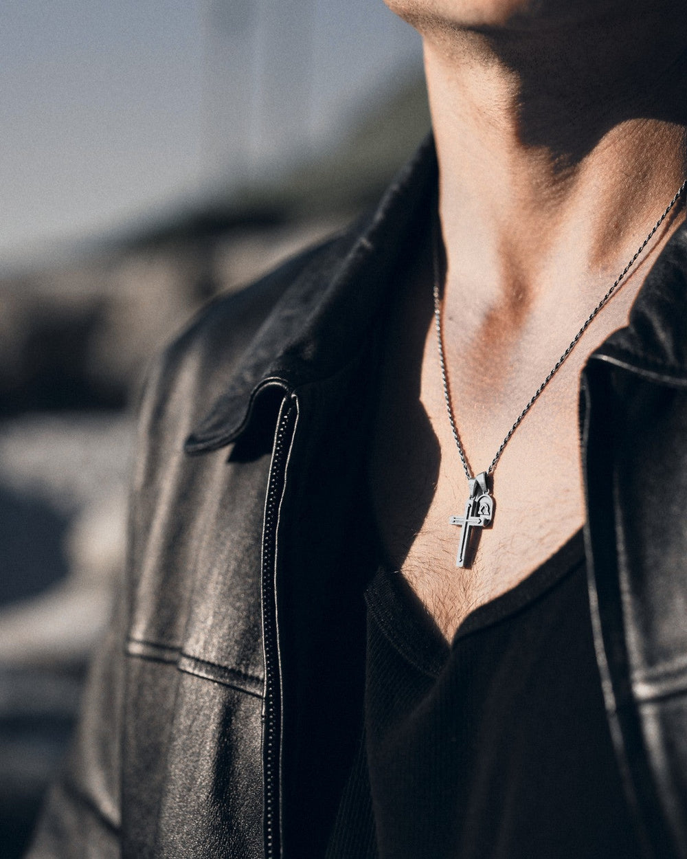Pax Cross in 925 sterling silver on a chain, worn under an open leather jacket.
