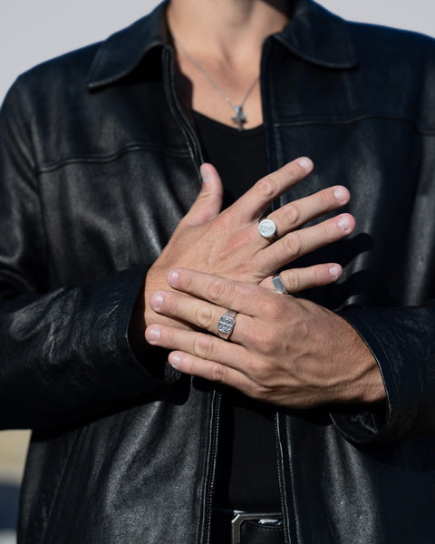 Aegis and ChiRho signet rings in 925 sterling silver on hands crossed over a black leather jacket.