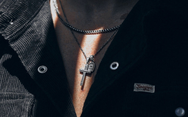 Pax Cross in 925 sterling silver worn over a black corduroy shirt, the cross and the oval tag resting on the chest.