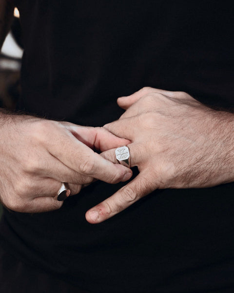 ChiRho signet ring in 925 sterling silver on clasped hands, over a black tee.