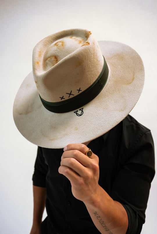 The Maxim Hat held at the brim in front of the face.