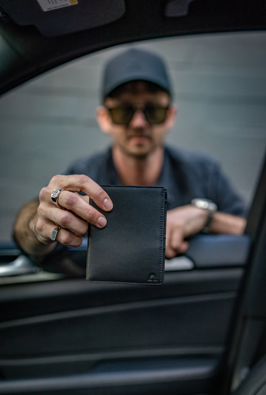 A black wallet held at a car window.