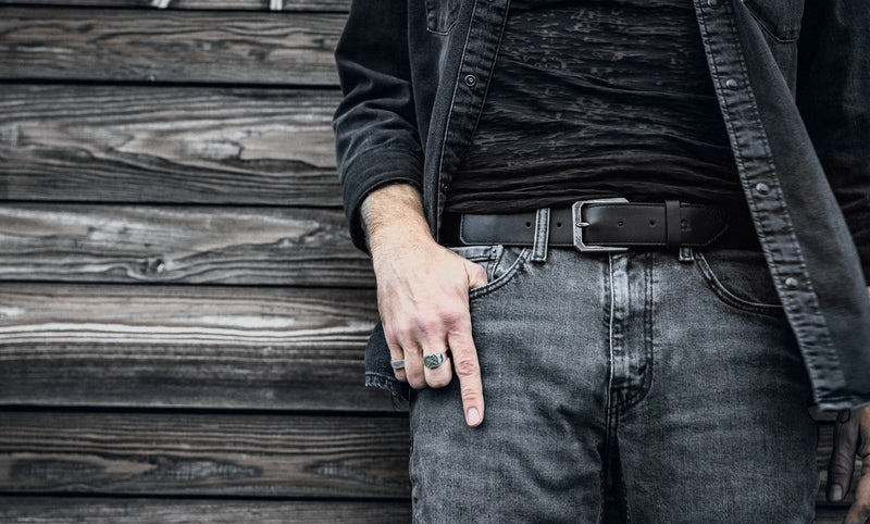 Praxis Belt in Onyx full-grain leather buckled at the waist with grey denim and a silver ring.