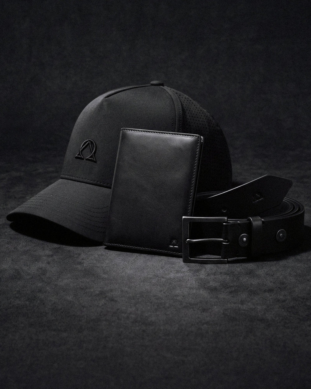 Lux Trucker hat, Virtus Belt, and Atlas Wallet in one colorway on a dark ground.